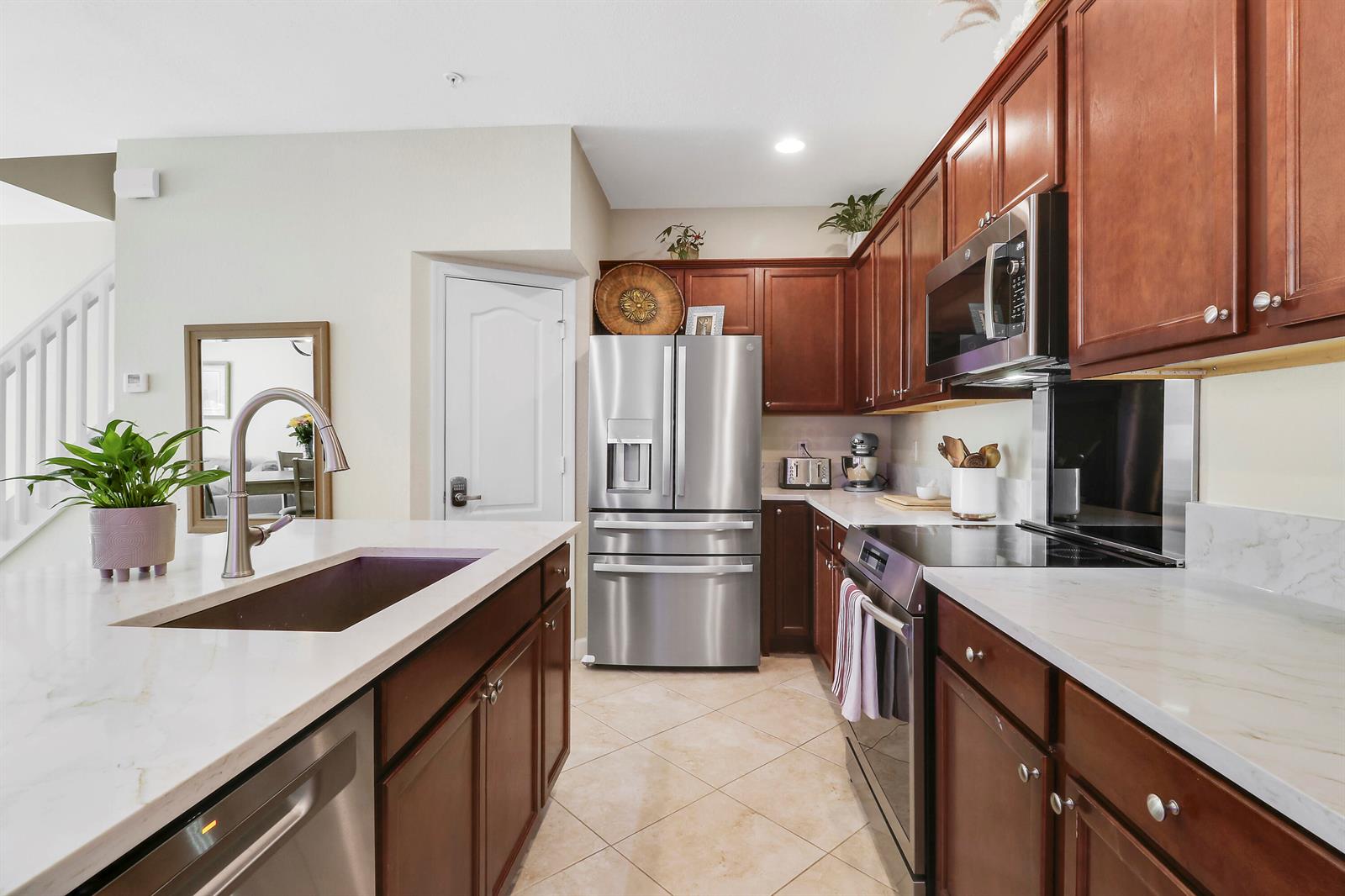 A kitchen features dark wood cabinets, stainless steel appliances, and a white quartz-topped island — 9504 SW Merlin Court, Stuart FL 34997, STUART, FL