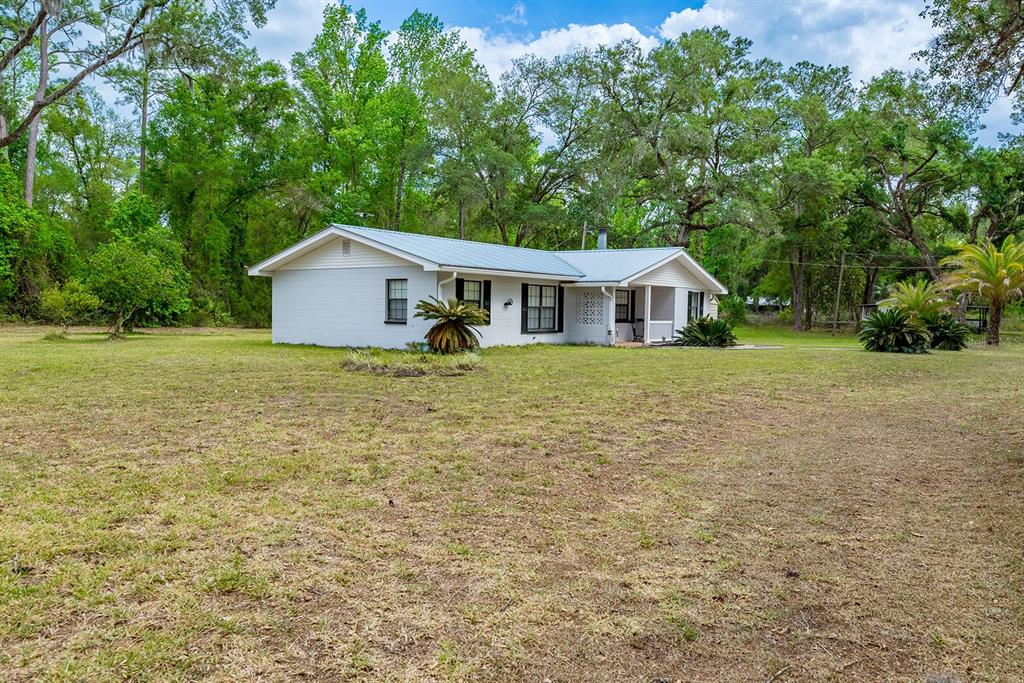 A single-story white house with a metal roof sits on a large, grassy lot — 1753 SE HIGHWAY 349, OLD TOWN, FL