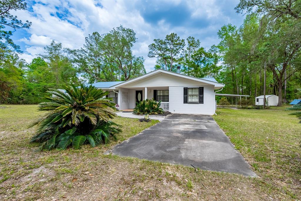 A white, single-story house with a concrete driveway and a large cycad in the yard — 1753 SE HIGHWAY 349, OLD TOWN, FL