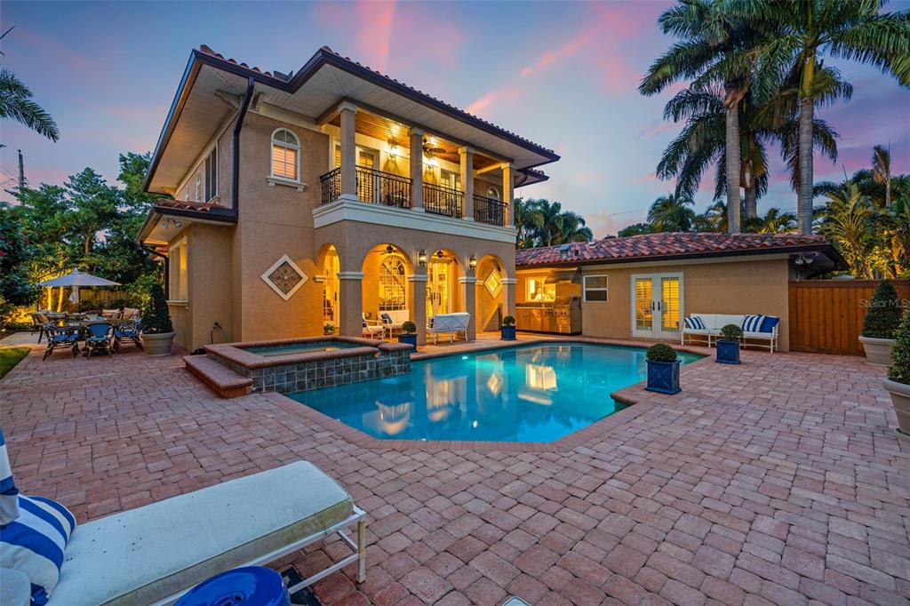 A two-story house with a pool, spa, and patio area at sunset — 1124 SEVILLE LANE NE, ST PETERSBURG, FL