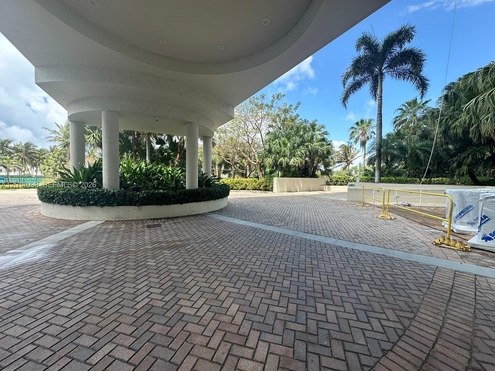 A paved driveway leads to a covered entrance with white columns and surrounding tropical landscaping — 6001 N Ocean Dr # 503, Hollywood FL 33019, HOLLYWOOD, FL