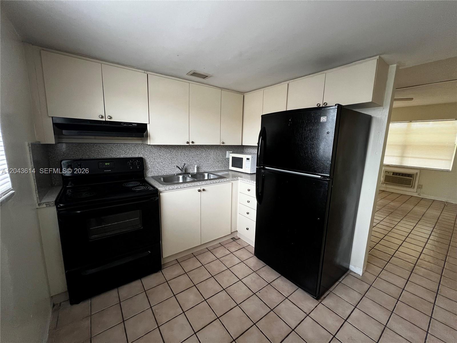 A kitchen features white cabinets, black appliances, a tiled floor, and a granite-style countertop — 13 NE 2nd Ave # 104, Dania Beach FL 33004, DANIA BEACH, FL