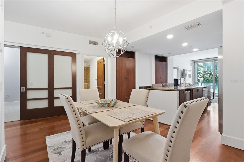 A dining area features a light wood table, upholstered chairs, and a modern globe chandelier — 111 N 12TH STREET UNIT 1325, TAMPA, FL