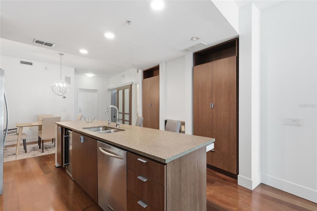 A kitchen island with a stainless steel dishwasher and sink sits before tall wooden cabinets — 111 N 12TH STREET UNIT 1325, TAMPA, FL