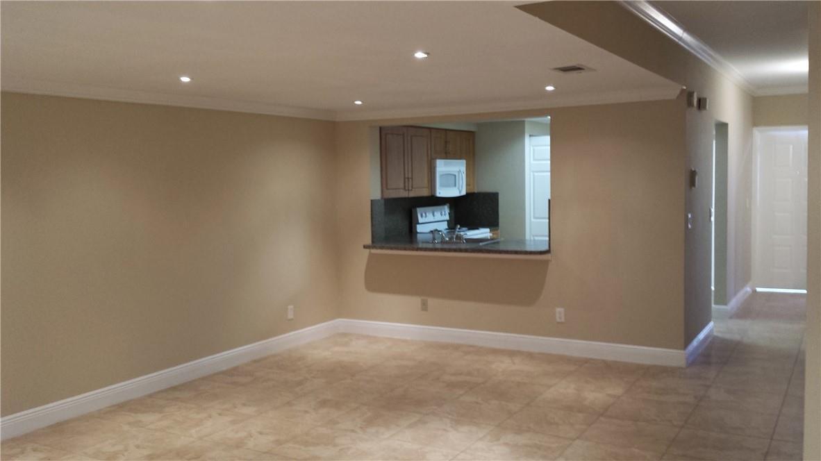 An open living area features beige walls, tile flooring, and a pass-through to the kitchen — 4728 NW 90th Avenue, Sunrise FL 33351, SUNRISE, FL