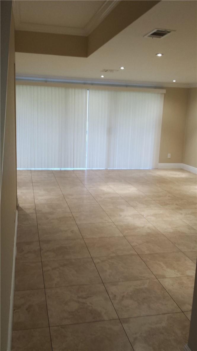 An empty room with large beige floor tiles and vertical blinds covering a sliding door — 4728 NW 90th Avenue, Sunrise FL 33351, SUNRISE, FL