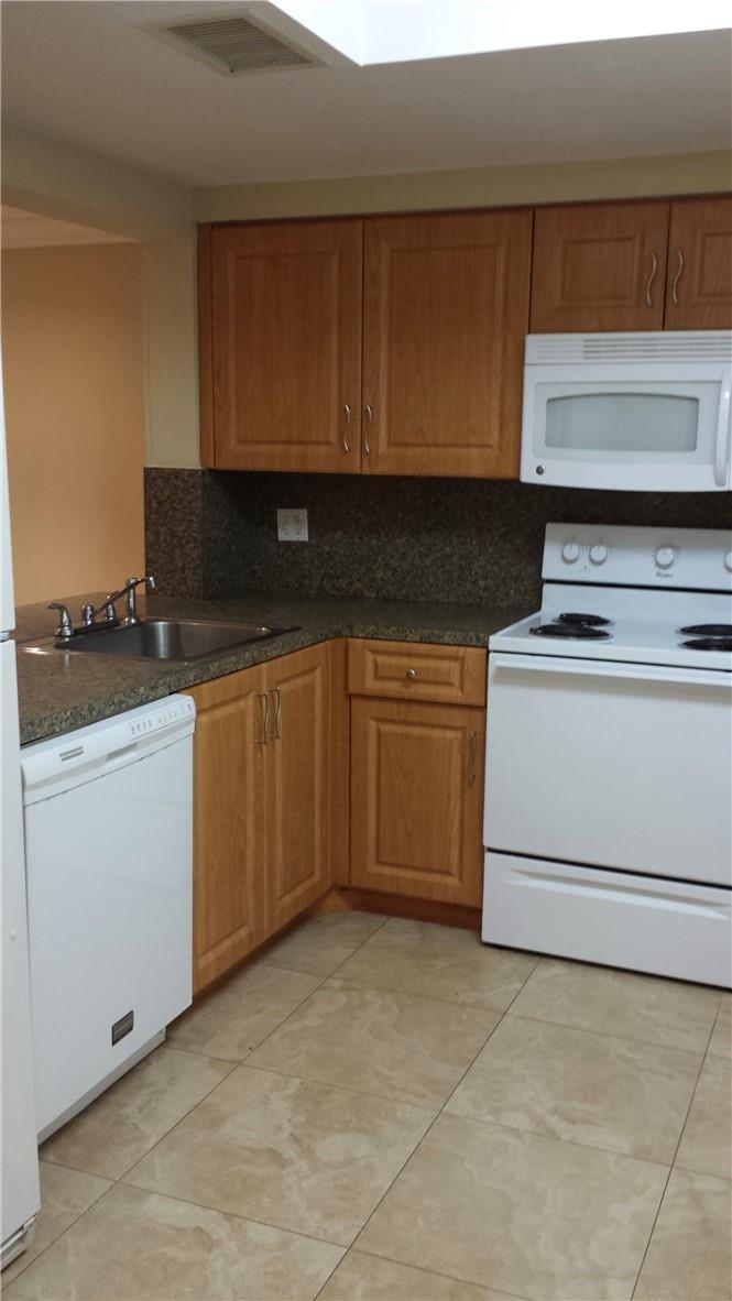A kitchen features light wood cabinets, granite countertops, white appliances, and beige tile flooring — 4728 NW 90th Avenue, Sunrise FL 33351, SUNRISE, FL