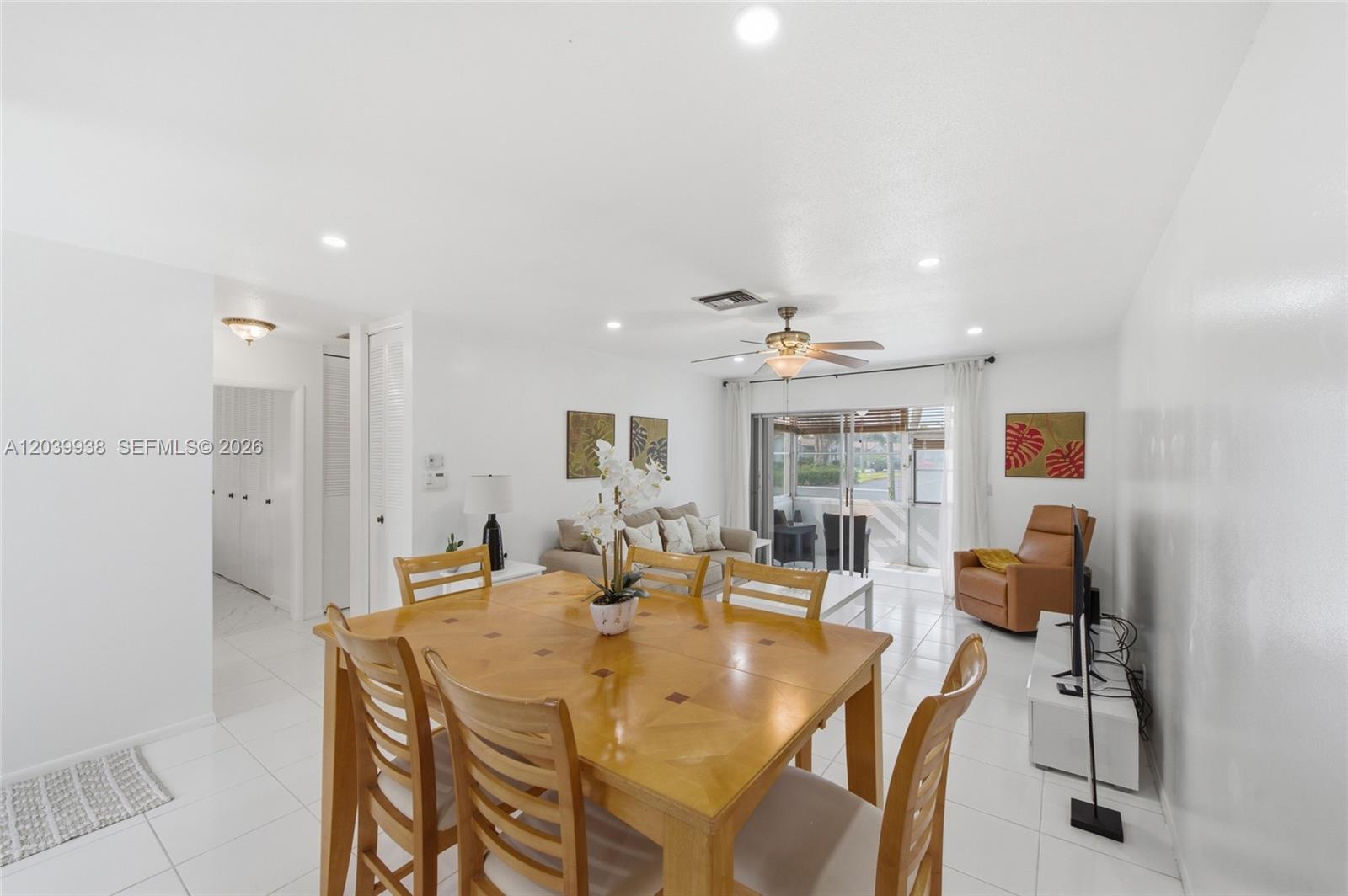 A dining area with a wooden table leads into a living room with white tile floors — 2894 E Crosley Dr E # D, West Palm Beach FL 33415, WEST PALM BEACH, FL