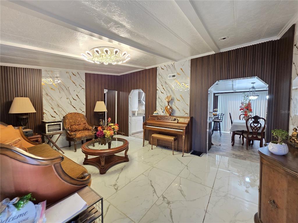 A living room features marble-look tile floors, wood-slat wall accents, and an upright piano — 11344 ROCKRIDGE ROAD, LAKELAND, FL