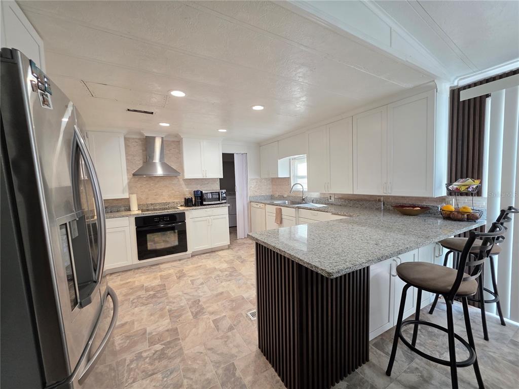 A kitchen features white cabinets, granite countertops, a stainless steel range, and a breakfast bar — 11344 ROCKRIDGE ROAD, LAKELAND, FL