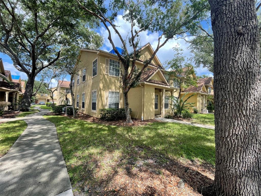 A two-story tan apartment building with a sidewalk and trees in the foreground — 850 GRAND REGENCY POINT UNIT 200, ALTAMONTE SPRINGS, FL