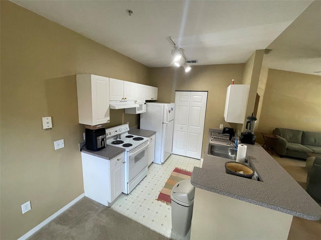 A kitchen features white cabinets, a white stove, a refrigerator, and a gray countertop — 850 GRAND REGENCY POINT UNIT 200, ALTAMONTE SPRINGS, FL