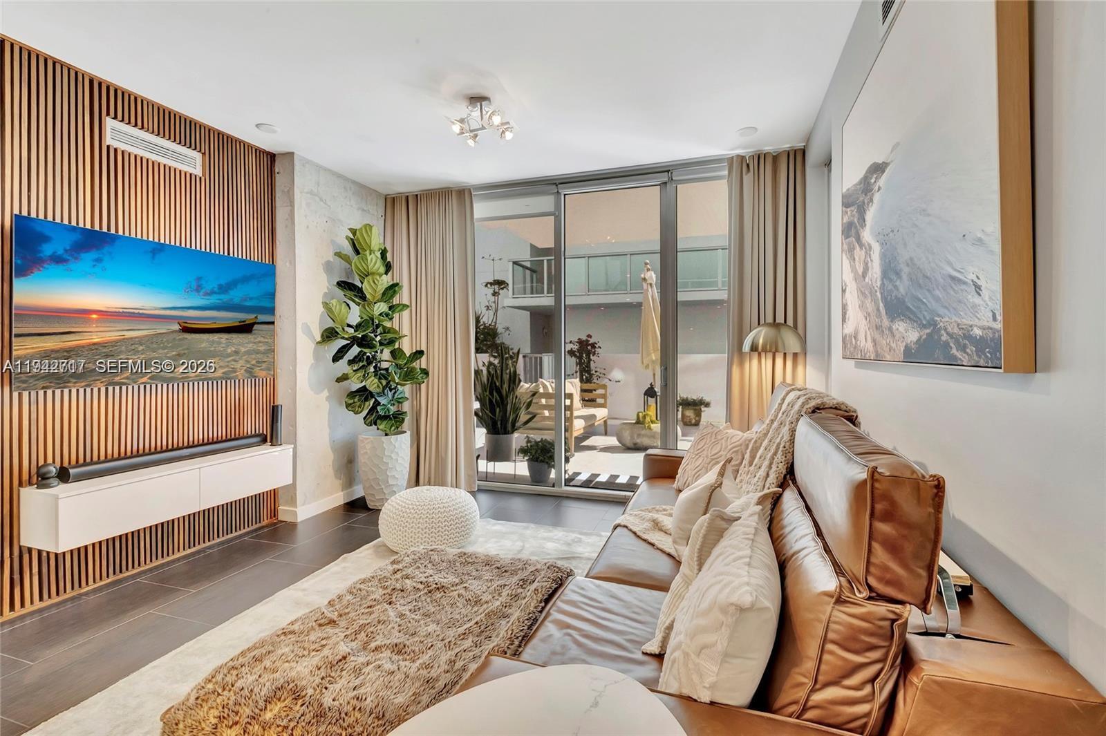 A modern living room features a wood-slatted accent wall, a leather sofa, and a balcony — 720 NE 62nd St # 307, Miami FL 33138, MIAMI, FL