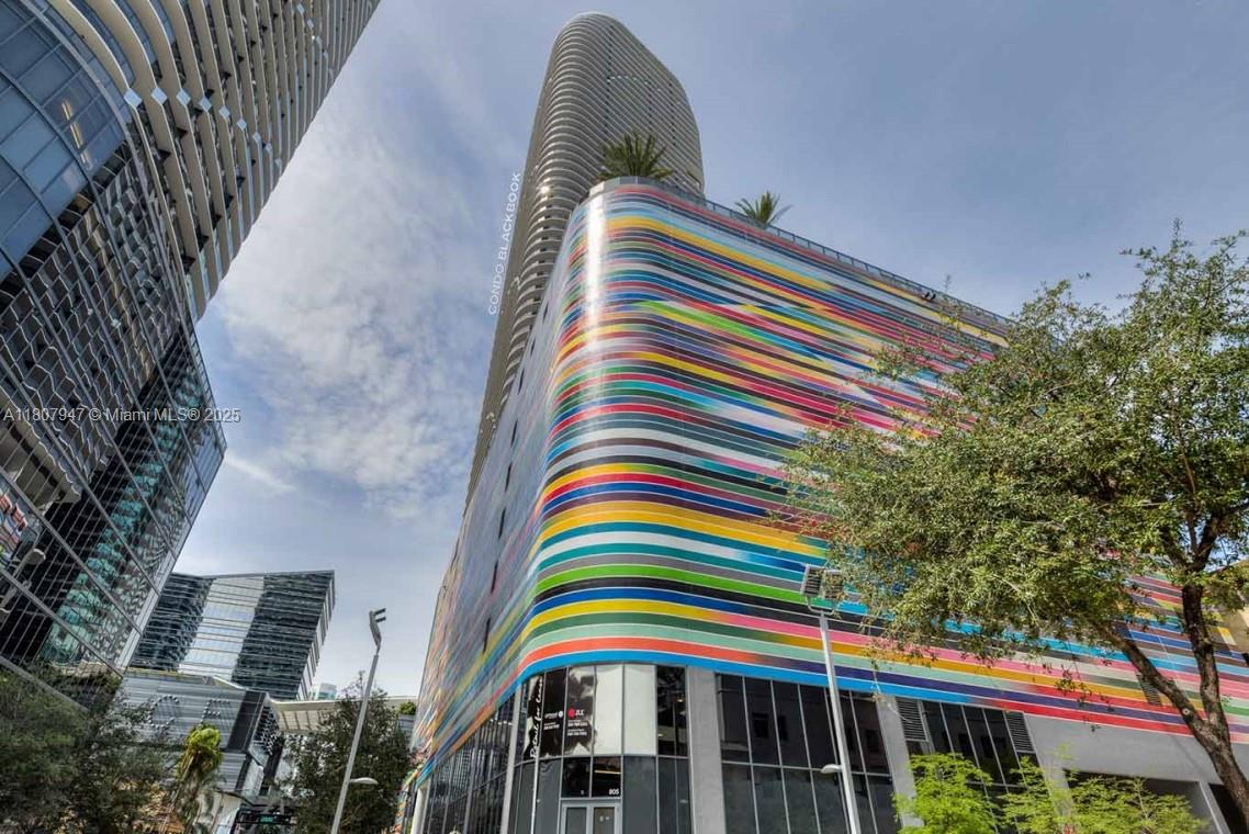 A low-angle exterior view of a modern building featuring a colorful, horizontally striped facade — 801 S Miami Ave # 2201, Miami FL 33130, MIAMI, FL