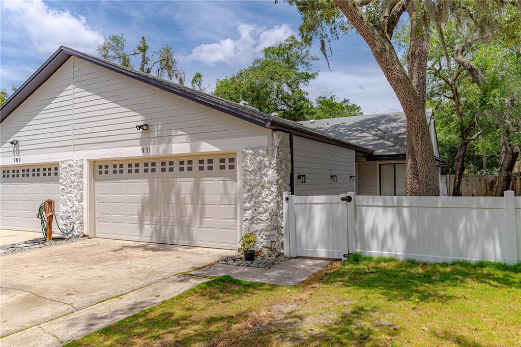 A beige house exterior features a two-car garage, stone accents, and a white vinyl fence — 911 ROBINHOOD COURT, MAITLAND, FL