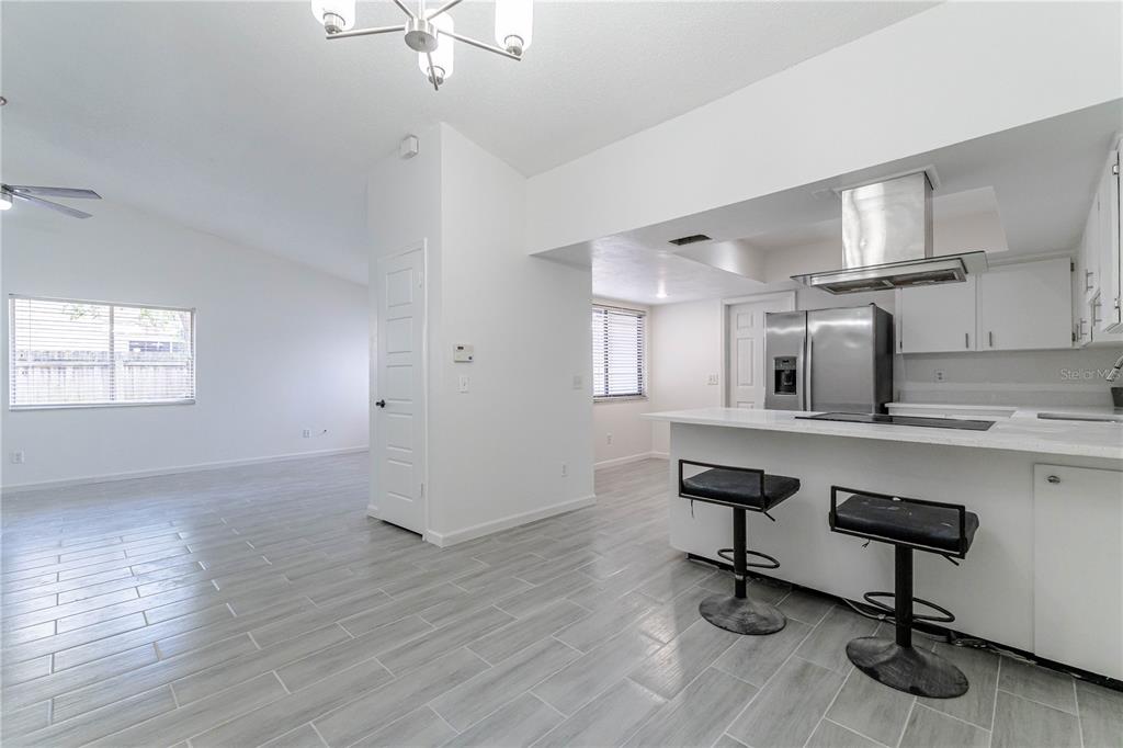 A kitchen with white cabinets and a breakfast bar overlooks an open living area — 911 ROBINHOOD COURT, MAITLAND, FL