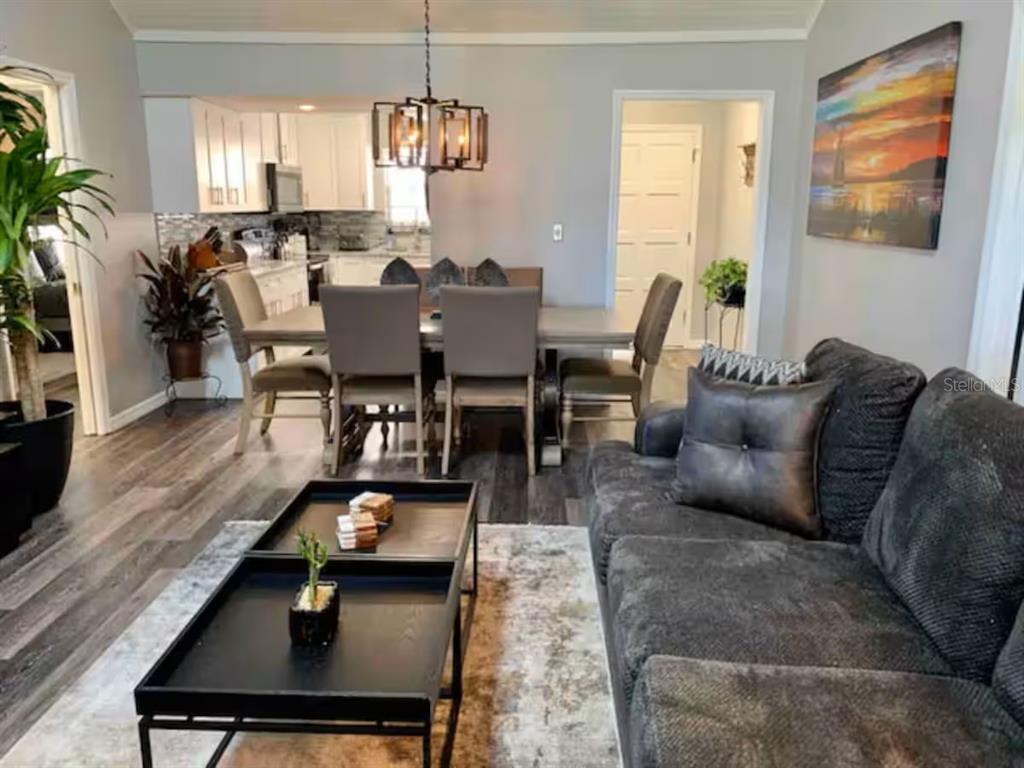 A living room with a dark sofa and coffee table opens to a dining area — 1160 VILLA LANE UNIT 108, APOPKA, FL