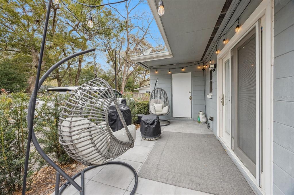 A covered patio features two hanging egg chairs, string lights, and a sliding glass door — 2218 ELIZABETH AVENUE UNIT 3, ORLANDO, FL