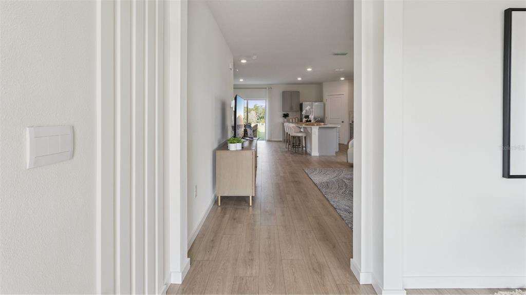 A view through a doorway into an open-concept living area with light wood flooring — 4910 MARSHELDER STREET, APOPKA, FL