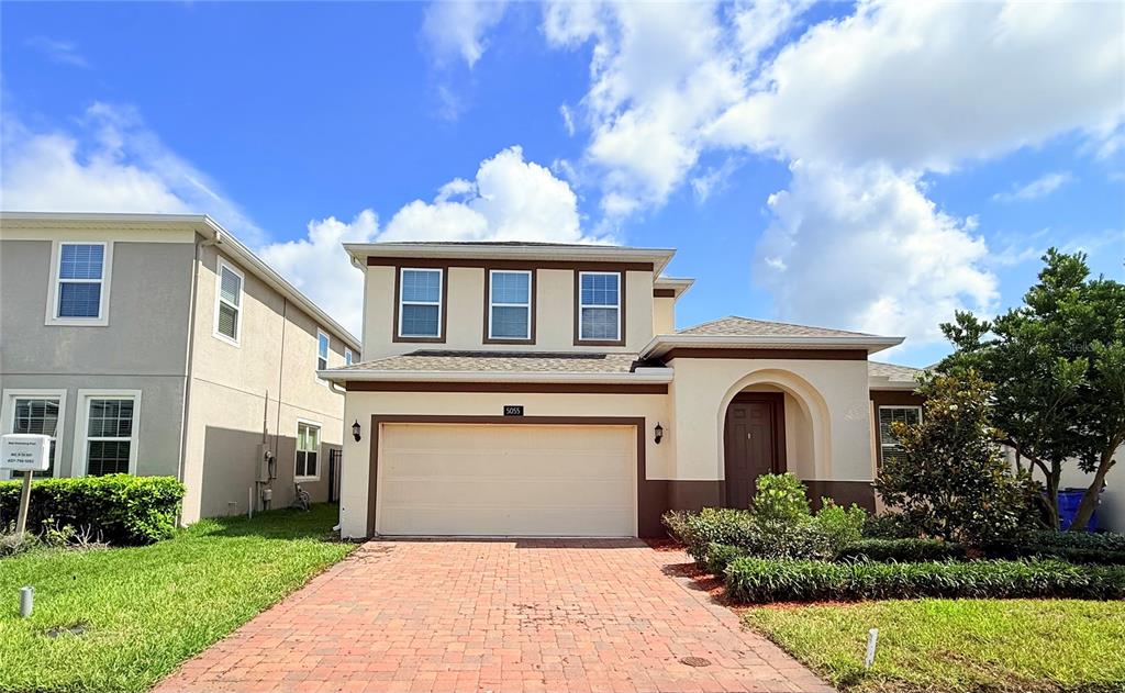 A two-story house with a brick driveway, a two-car garage, and a brown front door — 5055 TIBET COURT, ST CLOUD, FL