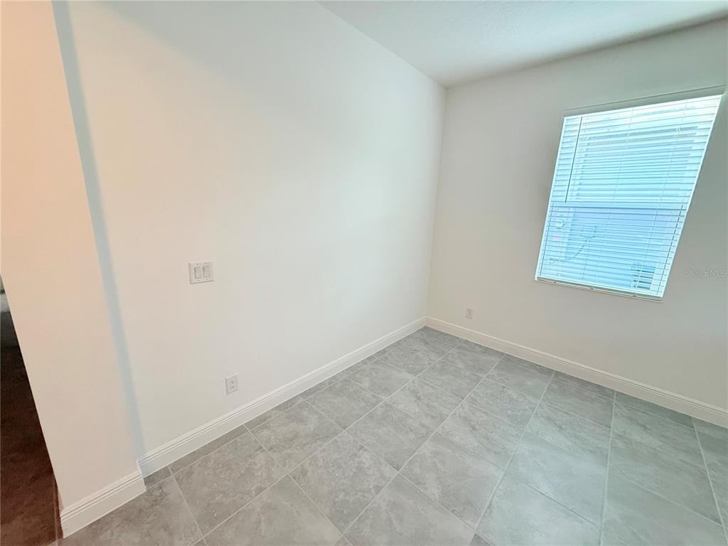 A small, empty room features white walls, light gray tile flooring, and a single window — 5055 TIBET COURT, ST CLOUD, FL