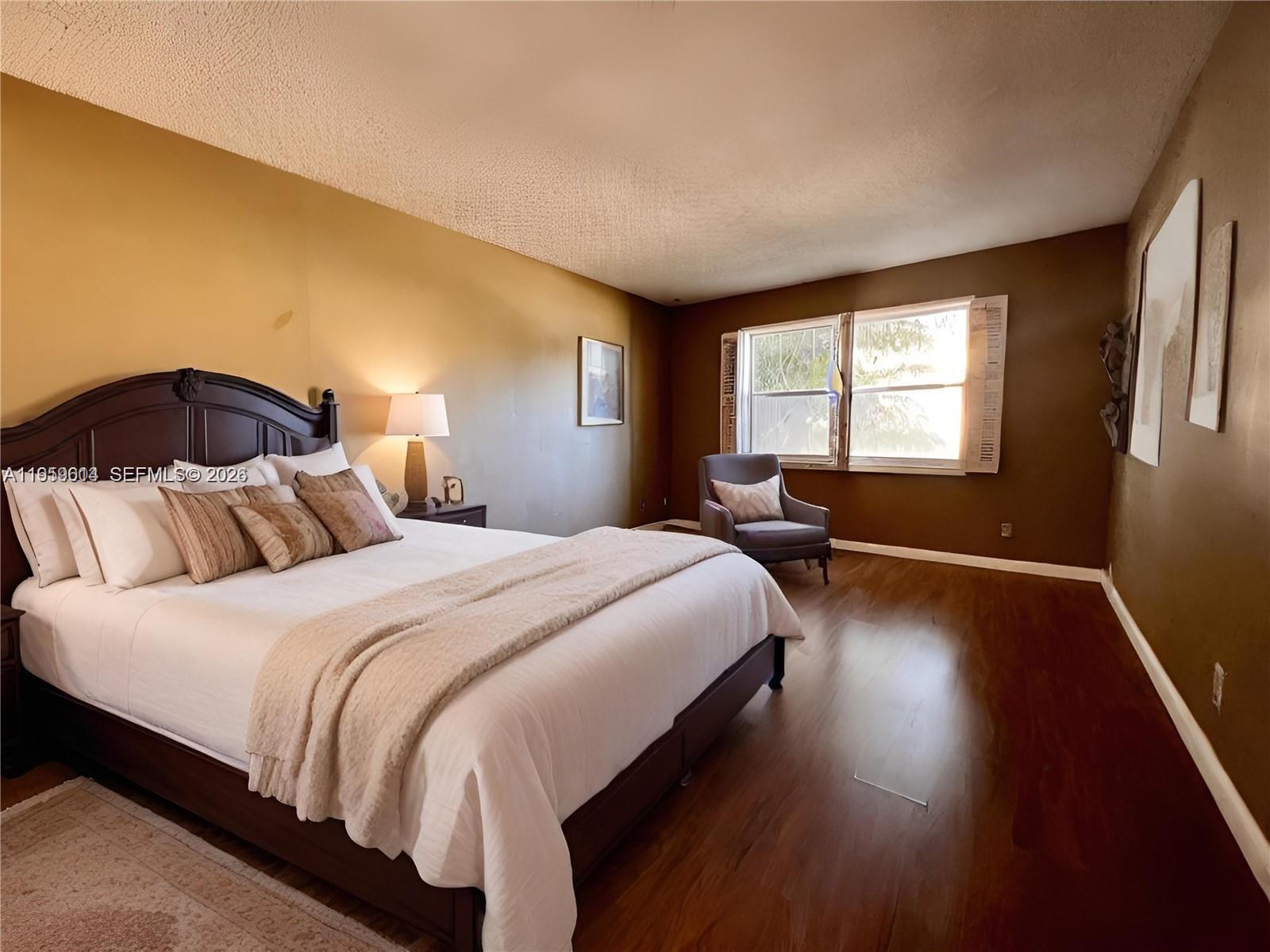 A bedroom features a dark wood bed frame, hardwood floors, and two-toned brown walls — 3300 Spanish Moss Ter # 206, Lauderhill FL 33319, LAUDERHILL, FL