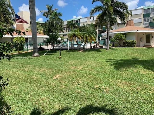 A grassy lawn leads to a multi-story apartment building with palm trees and a pool — 1333 E Hallandale Beach Blvd # 131, Hallandale Beach FL 33009, HALLANDALE BEACH, FL