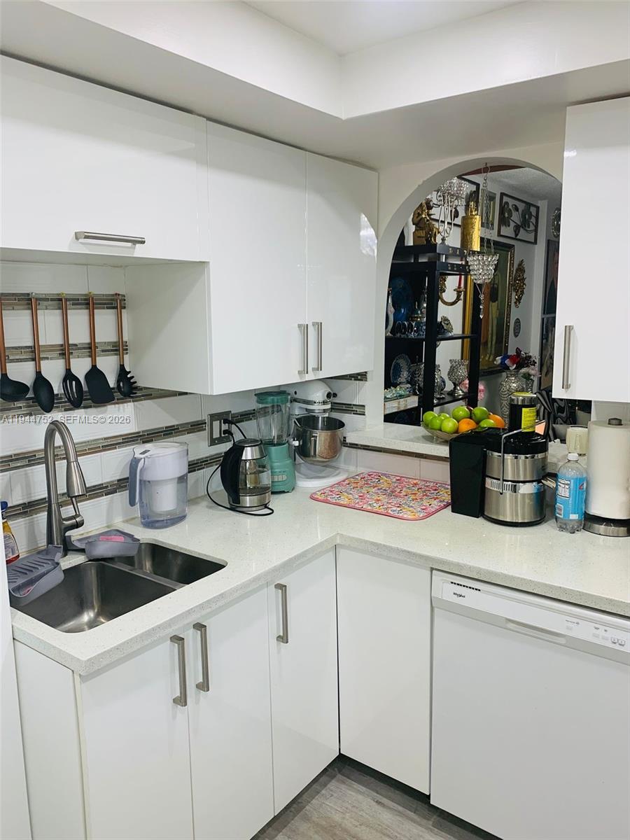 A white kitchen features quartz countertops, stainless steel appliances, and an arched opening to another room — 1333 E Hallandale Beach Blvd # 131, Hallandale Beach FL 33009, HALLANDALE BEACH, FL