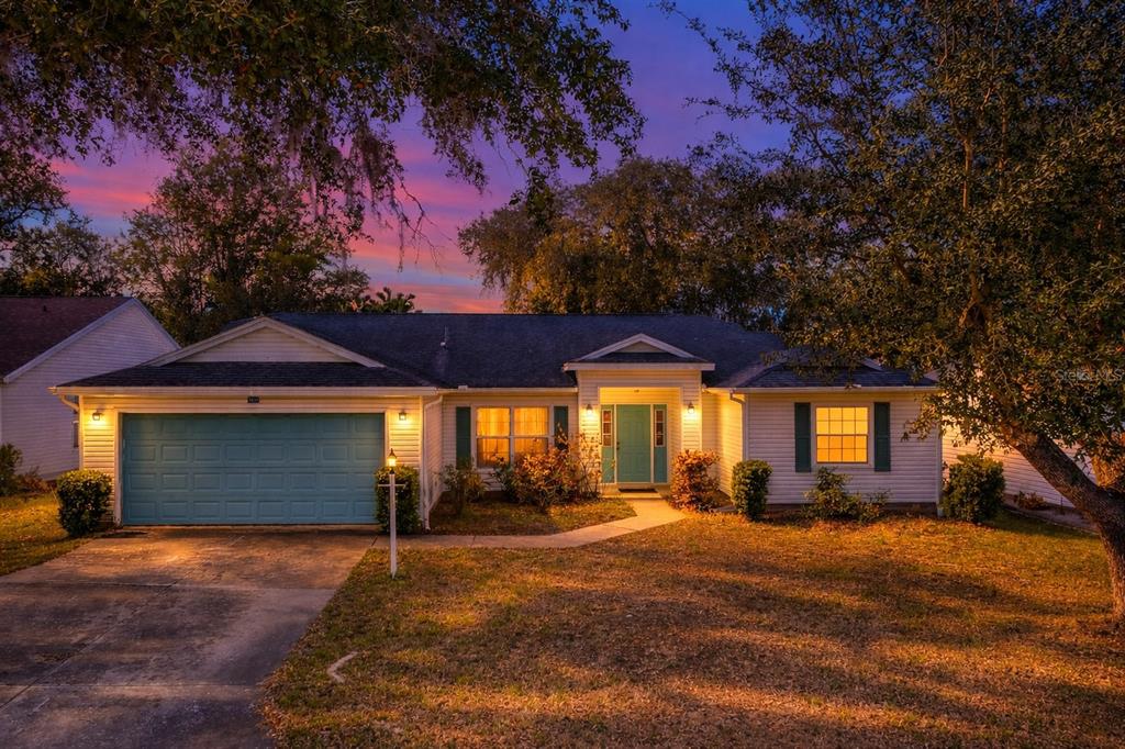 A single-story house with a teal garage door and front door at dusk — 3850 PLANTATION BOULEVARD, LEESBURG, FL