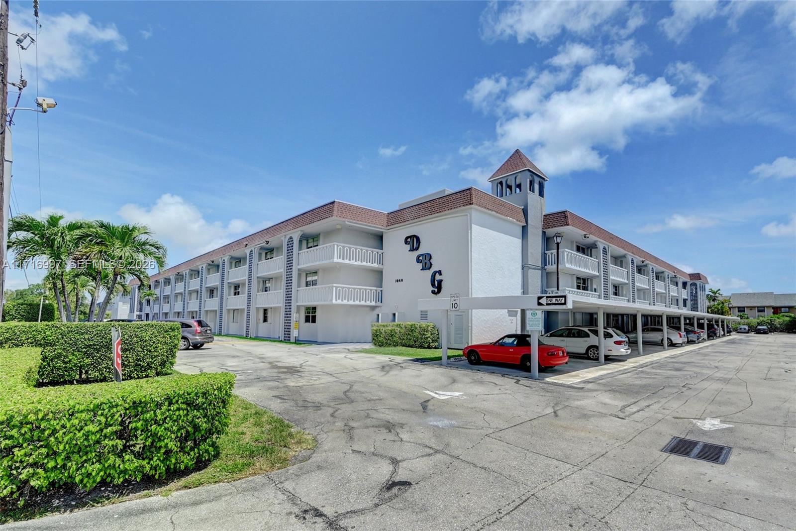 A three-story apartment building with a covered parking area and a landscaped hedge — 1040 SE 4th Ave # 128, Deerfield Beach FL 33441, DEERFIELD BEACH, FL
