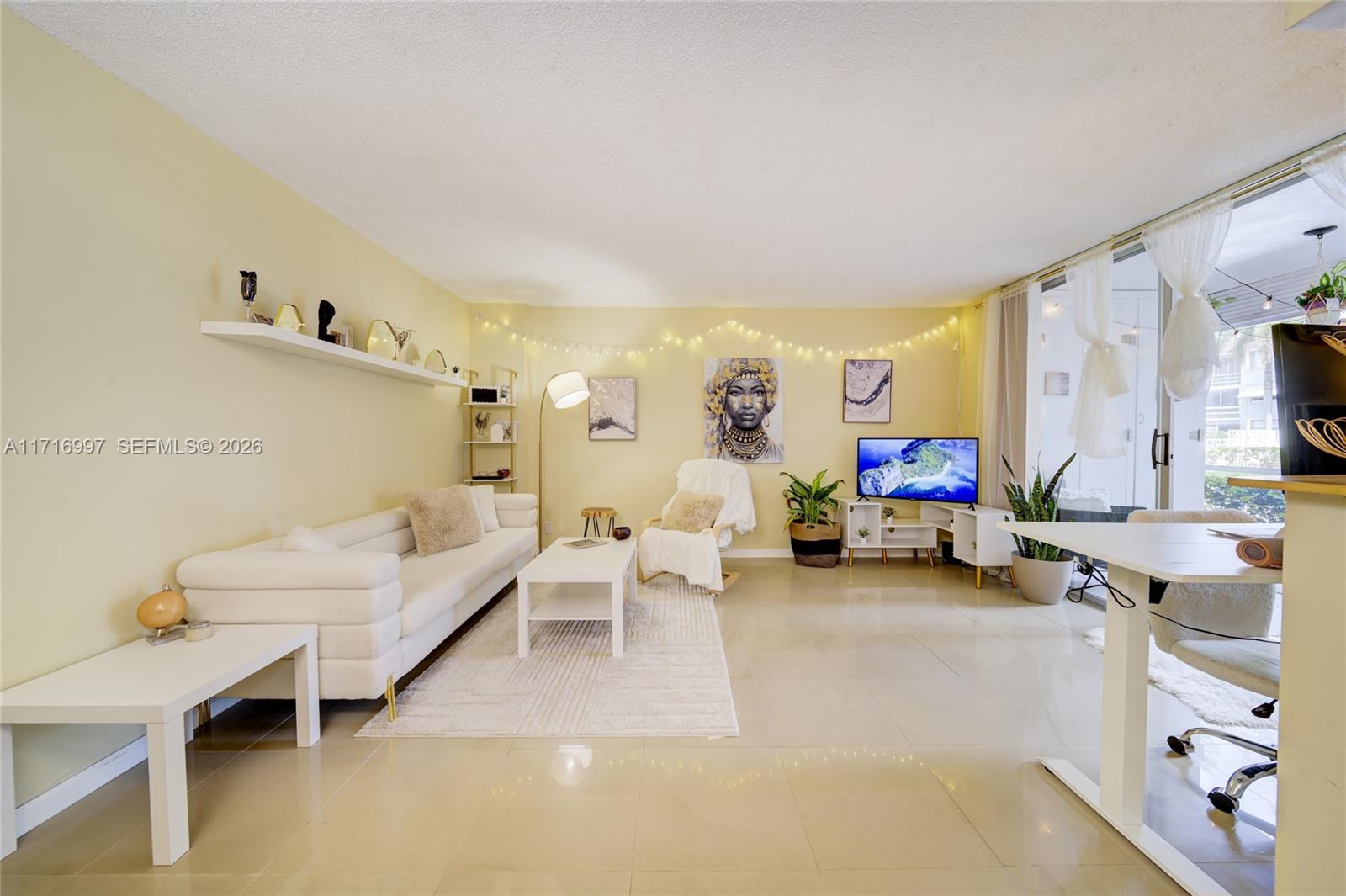 A living room features a white sofa, a coffee table, and a television on a stand — 1040 SE 4th Ave # 128, Deerfield Beach FL 33441, DEERFIELD BEACH, FL