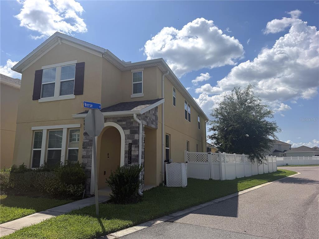 A two-story tan house with a stone-accented entryway and a white vinyl fence — 15175 CHAPTER WAY, WINTER GARDEN, FL