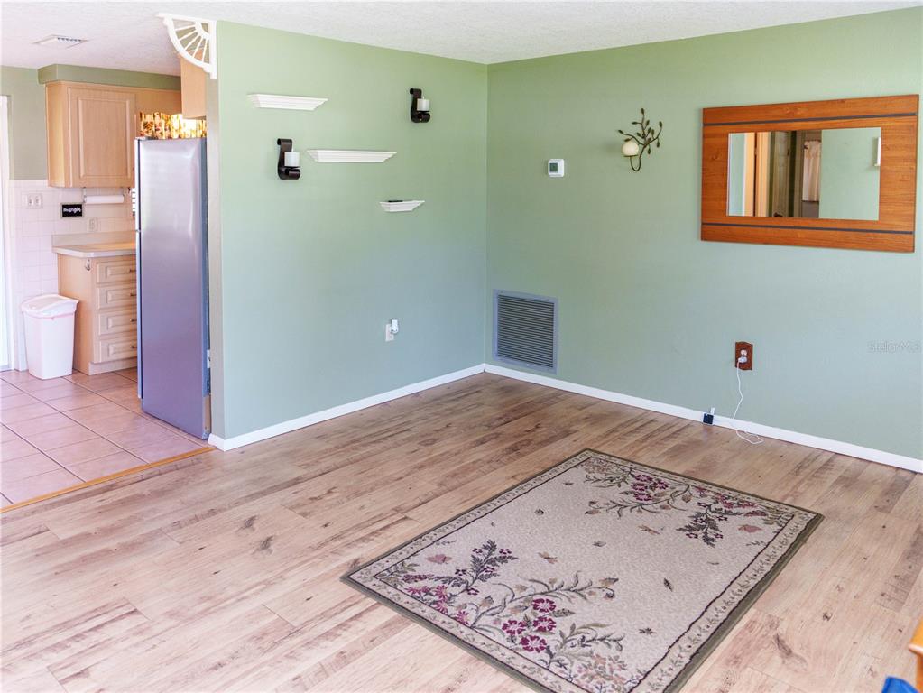 A living room with sage green walls, wood-look flooring, and an area rug — 6155 ILLINOIS AVENUE, NEW PORT RICHEY, FL