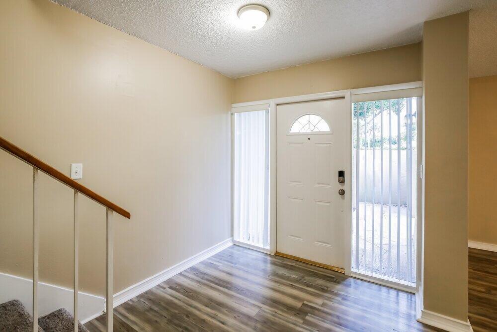 An entryway features wood-look flooring, a white front door with sidelights, and a staircase railing — MIAMI, FL
