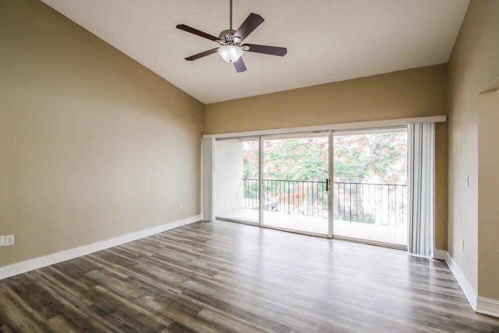 An empty room with wood-look flooring, a ceiling fan, and sliding glass doors to a balcony — MIAMI, FL