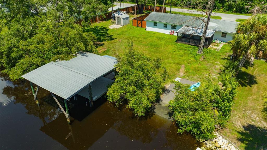 An aerial view shows a waterfront house with a boat dock and a small shed — 9935 RIVER DRIVE, GIBSONTON, FL