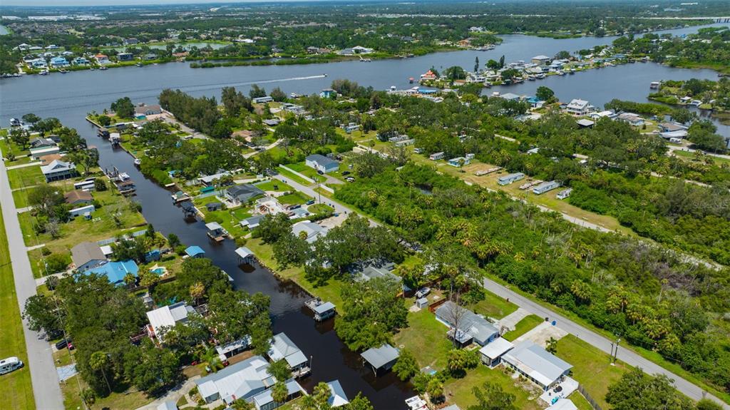 An aerial view shows houses along a canal leading to a larger body of water — 9935 RIVER DRIVE, GIBSONTON, FL