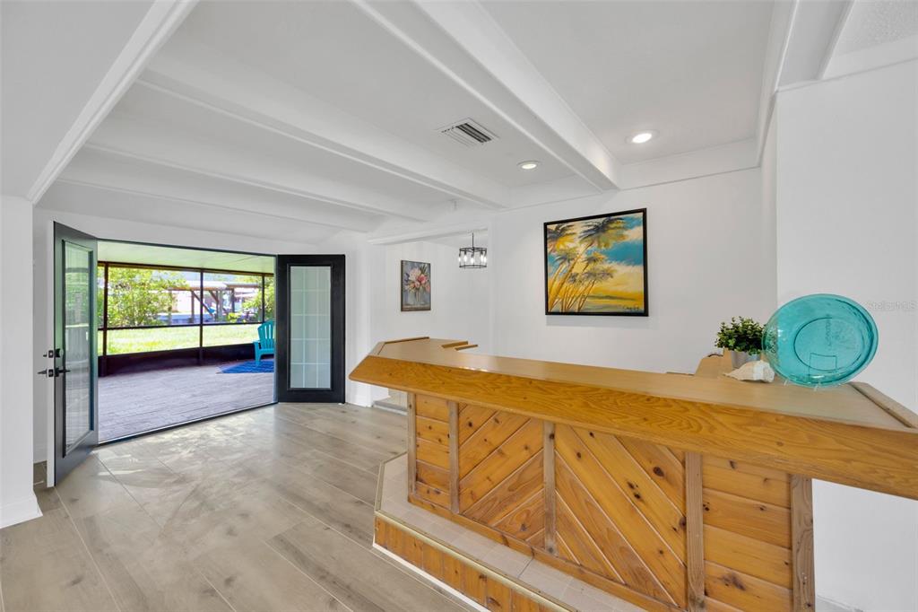 A room with a wooden bar, light wood flooring, and double doors opening to a patio — 9935 RIVER DRIVE, GIBSONTON, FL