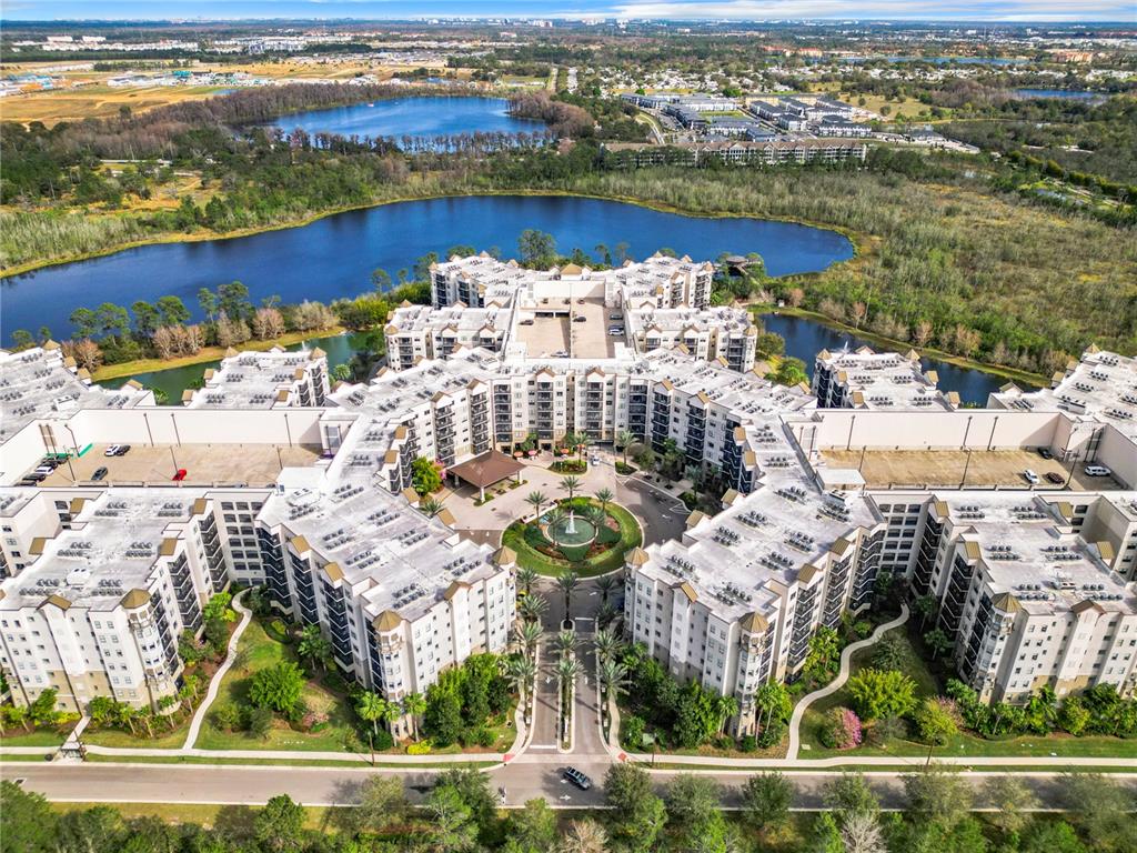 An aerial view shows a large, multi-story apartment complex surrounded by lakes and green space — 14501 GROVE RESORT AVENUE UNIT 3327, WINTER GARDEN, FL