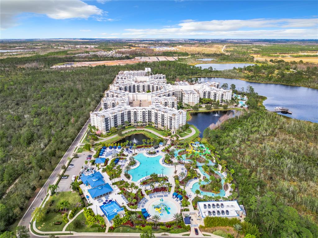 Aerial view of a large resort complex featuring multiple swimming pools, water slides, and surrounding lakes — 14501 GROVE RESORT AVENUE UNIT 3327, WINTER GARDEN, FL