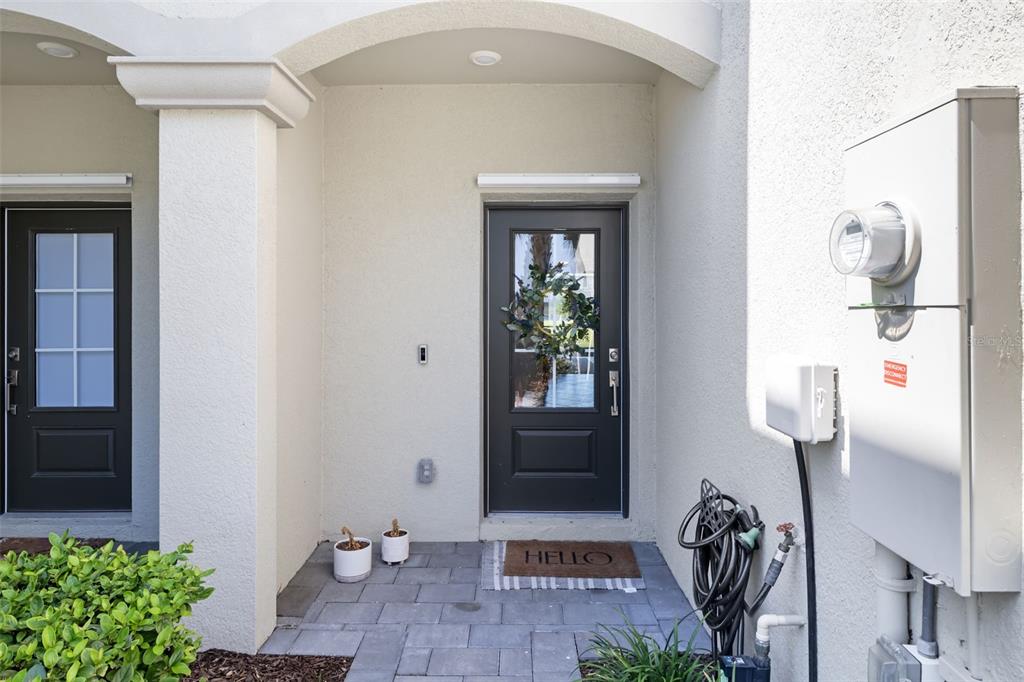 An exterior view of a home entrance featuring two dark doors and a paved porch — 15210 SUNNY DAY DRIVE, BRADENTON, FL