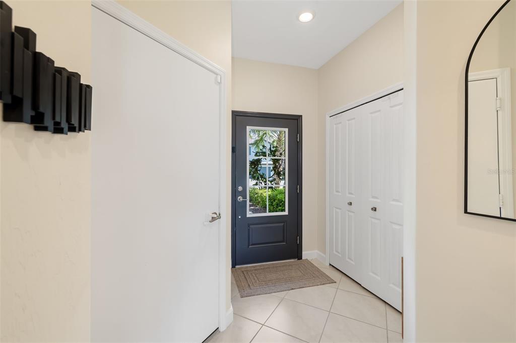 An entryway features a dark gray front door, white closet doors, and light tile flooring — 15210 SUNNY DAY DRIVE, BRADENTON, FL