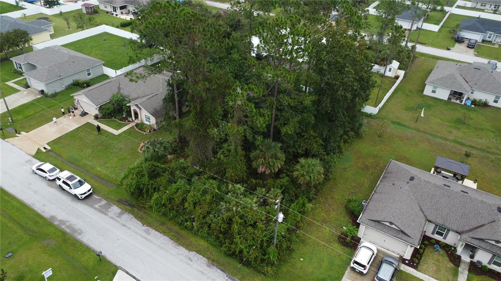 An aerial view shows a vacant, wooded lot situated between two residential houses — 24 FORSYTHE LANE, PALM COAST, FL