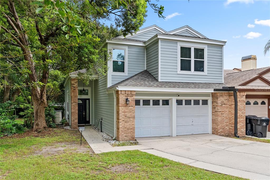 A two-story house with light blue siding, brick accents, and a two-car garage — 5305 DENVER DRIVE, ORLANDO, FL