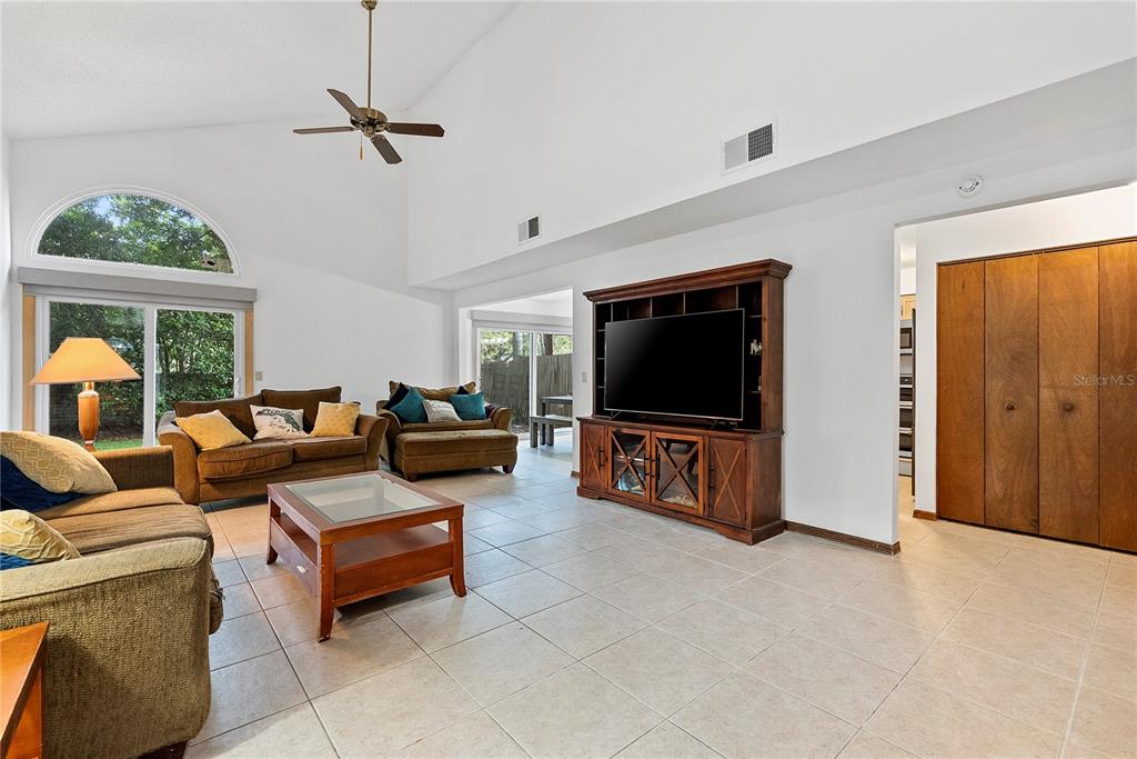 A living room features vaulted ceilings, tile flooring, a large entertainment center, and sliding doors — 5305 DENVER DRIVE, ORLANDO, FL