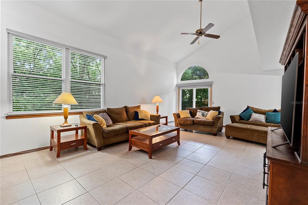 A living room features tile flooring, a vaulted ceiling, and three brown sofas — 5305 DENVER DRIVE, ORLANDO, FL