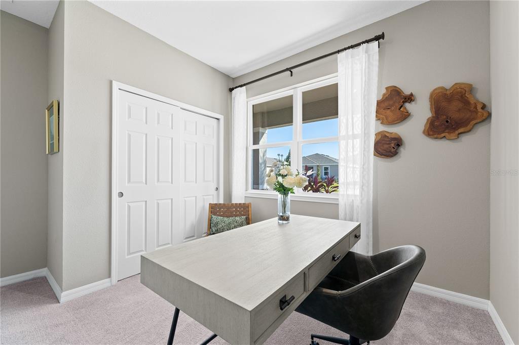 A home office features a light wood desk, a dark chair, and wall-mounted wood decor — 6751 WINTERBERRY DRIVE, LAKE HAMILTON, FL