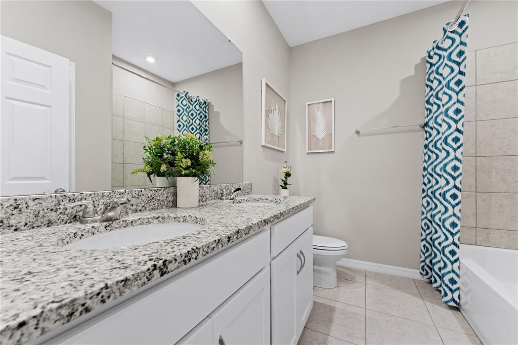 A bathroom features a granite vanity, white cabinets, a mirror, and a shower with patterned curtains — 6751 WINTERBERRY DRIVE, LAKE HAMILTON, FL