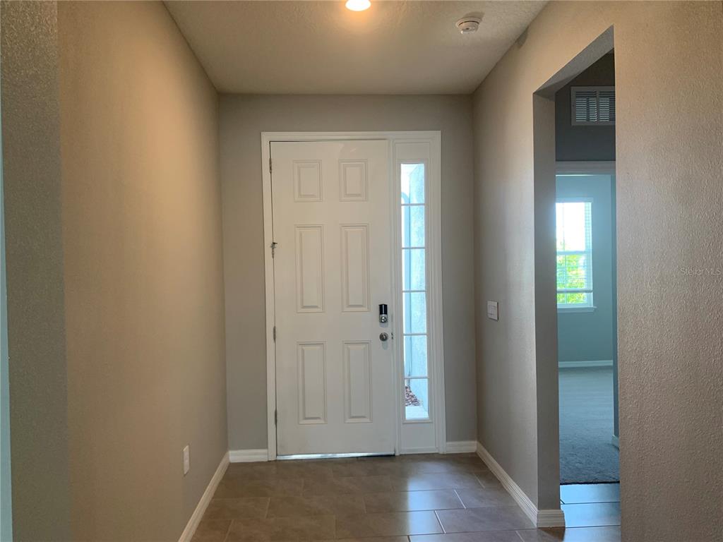 An entryway features a white front door with a sidelight, tile flooring, and neutral walls — 2012 MIDNIGHT PEARL DRIVE, SARASOTA, FL