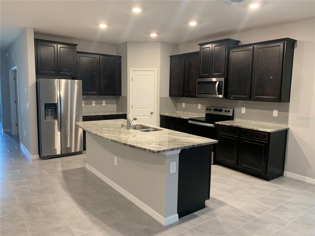 A kitchen features dark wood cabinets, granite countertops, a center island, and stainless steel appliances — 2012 MIDNIGHT PEARL DRIVE, SARASOTA, FL